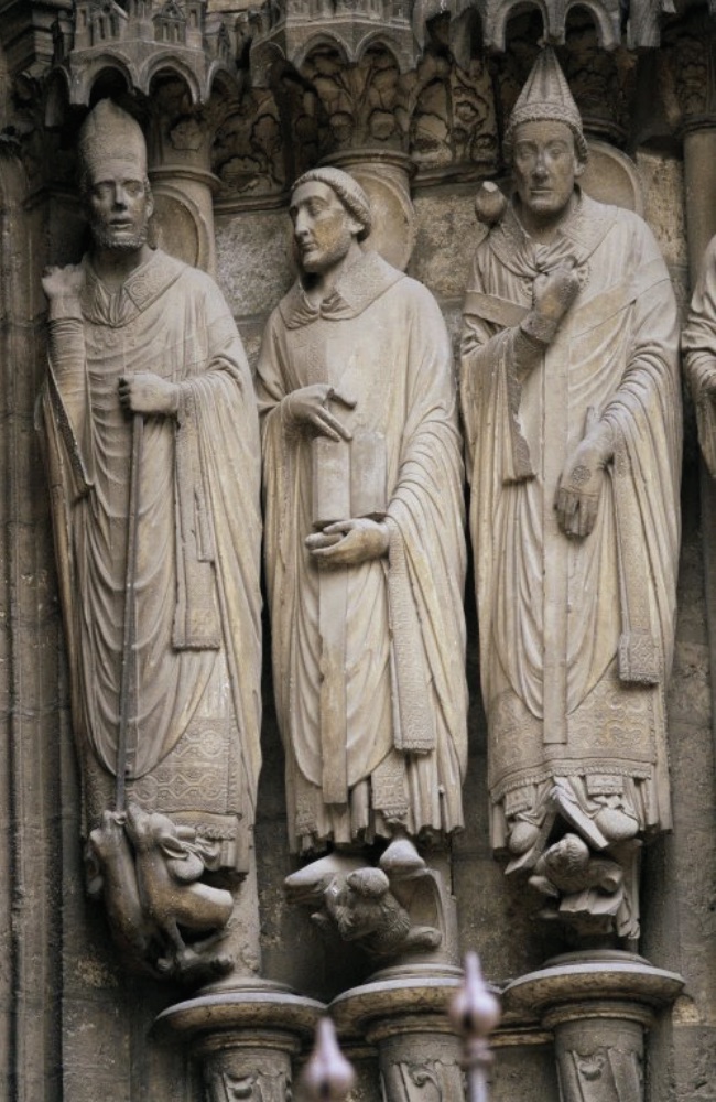 Photo of sculptures of three saints in robes standing next to one another.