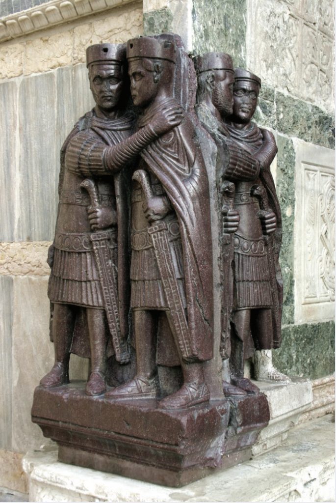 Photo of sculpture of emperors with arms around one another.