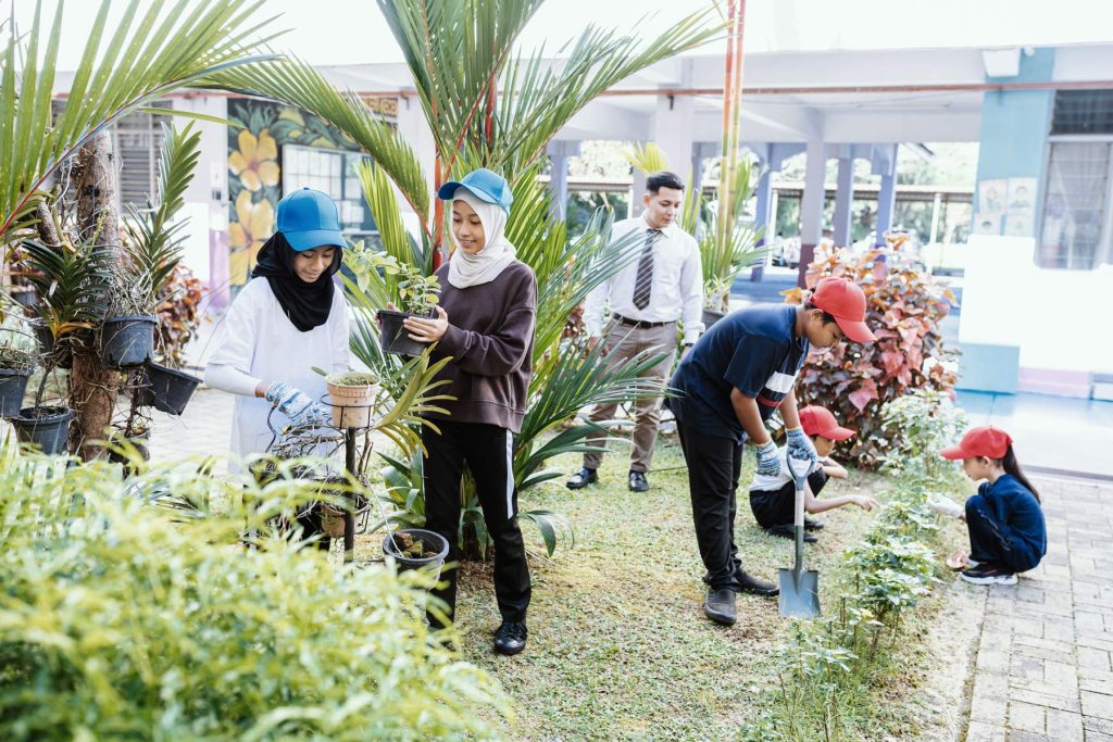 Happy school children seeding and planting in the school yard, raising awareness about environmental conservation.